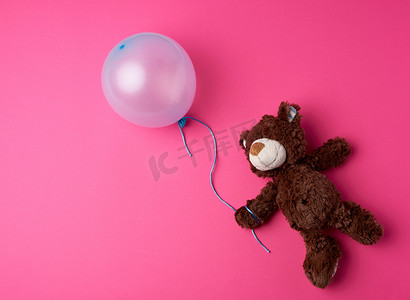 拿着蓝色充气气球的棕色小泰迪熊