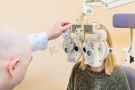 一名男性眼科医生使用综合屈光检查仪检查女孩的视力。