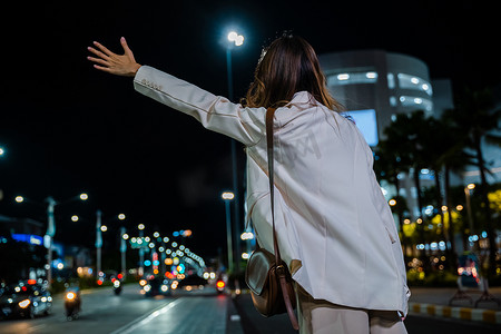 晚上，在繁忙的城市街道上，女商人站在路上挥舞着出租车