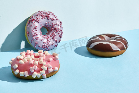 甜甜摄影照片_焦糖和巧克力糖衣的三个甜甜甜甜圈，两种颜色的背景