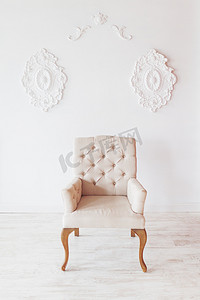 白色墙壁背景上的米色椅子与漩涡装饰。