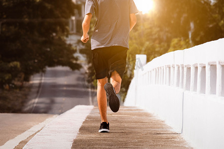 运动跑步背景摄影照片_在城市桥路上跑步的年轻人跑步脚正在跑步锻炼。