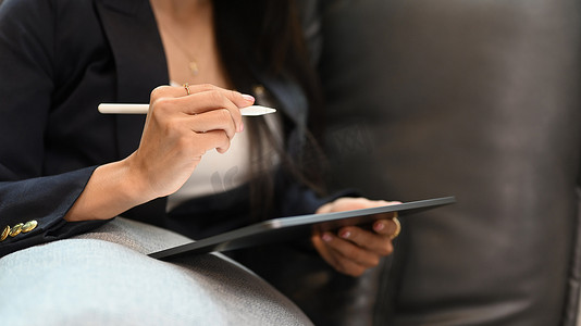 女性企业家坐在个人办公室的沙发上并使用数字平板电脑的剪影