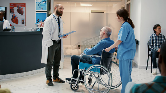 男医生在接待大厅会见坐轮椅的老病人
