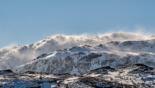 在清澈的蓝天背景下，挪威诺尔兰博多的白雪皑皑的山景全景。