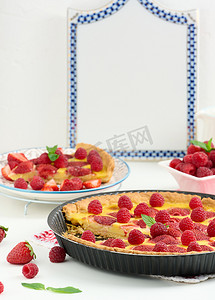 白桌上的圆形乳蛋饼，上面有红草莓和覆盆子，顶视图
