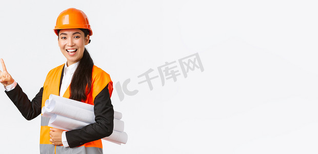 微笑自信的亚洲女工程师，安全头盔的施工经理，携带蓝图，展示两根手指，确保建筑按时完工，站立的白色背景乐观