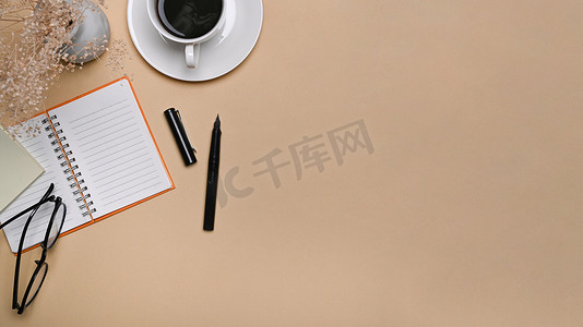 顶视图简单的工作区、一杯咖啡和米色背景的笔记本。