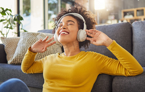 年轻快乐的混血女人戴着耳机，在家听音乐。