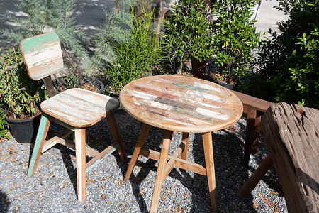 老式木桌和椅子放在后院的热带花园里。