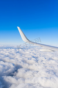 飞机白色机翼在蓝蓝的天空中飞过云层的视图。