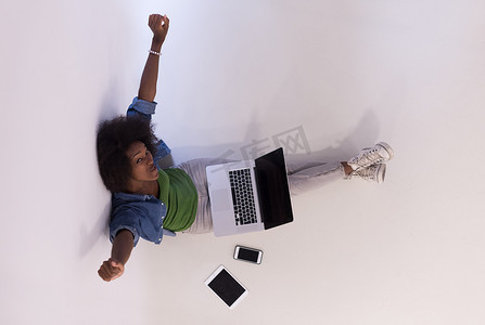 非洲裔美国女性坐在地板上，笔记本电脑俯视