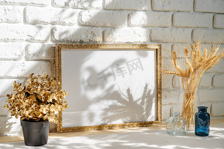 麦穗装饰摄影照片_桌上砖墙背景上的相框，花瓶里有麦穗