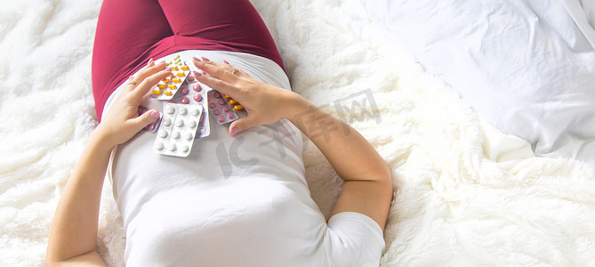一名孕妇手里拿着许多药片。