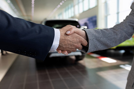 在汽车经销店交易的背景下握手，以租赁方式购买汽车的概念