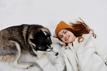 冬天遛狗摄影照片_在雪地里遛狗的女人冬装肖像