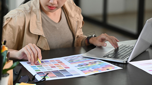 裁剪镜头平面设计师女性在办公桌上使用调色板。