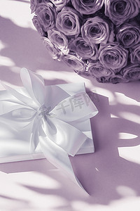 豪华假日丝绸礼盒和紫色背景的玫瑰花束、浪漫惊喜和鲜花作为生日或情人节礼物
