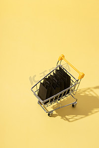 黄色背景黑色星期五销售中带购物袋的微型超市推车