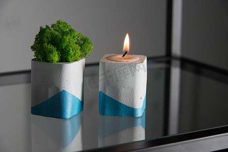 白色和蓝色混凝土烛台中的蜡烛和苔藓