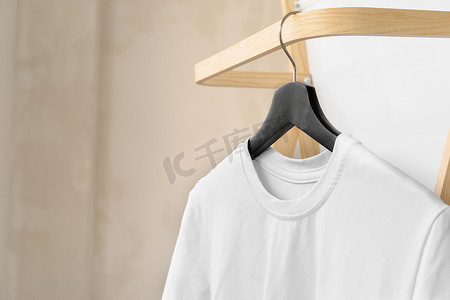 纯白色棉质 T 恤挂在衣架上，适合您的设计