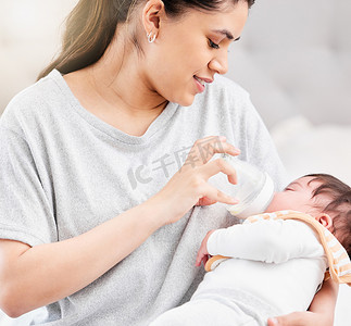 婴儿与奶瓶摄影照片_年轻的西班牙裔母亲给刚出生的婴儿喂奶瓶，并与她建立亲密关系。