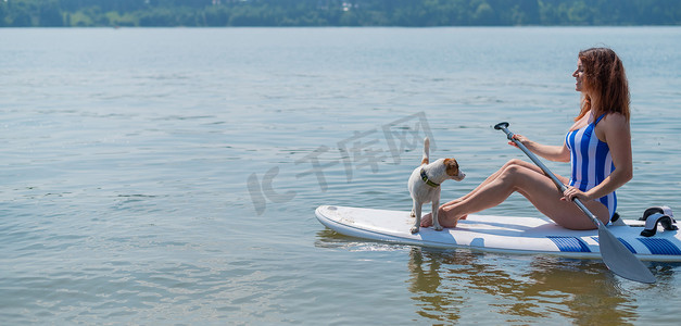 一位女士带着一只狗在湖上骑着冲浪板