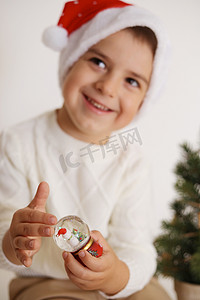 小男孩在白色背景上拿着圣诞雪球。