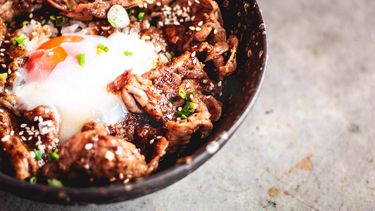 韩国猪肉加鸡蛋放在碗陶瓷盘里的米饭上，配有金属勺子和叉子。
