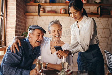 老年餐厅摄影照片_情侣、餐厅和约会，一对老年男女通过手机支付账单。