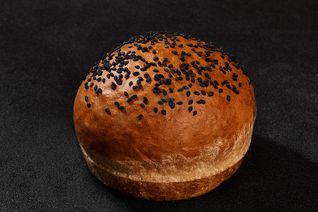 撒芝麻摄影照片_新鲜可口的烤面包撒上芝麻，黑色背景，带复制空间。