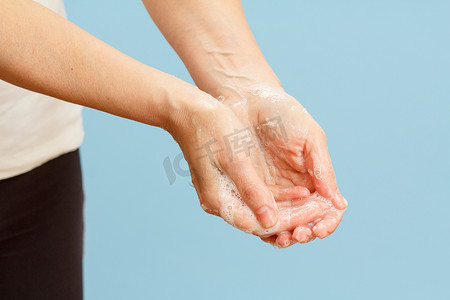 女人在蓝色背景上用肥皂洗手。