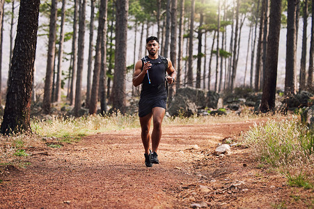 年轻的混合种族适合男运动员在大自然的森林里跑步。