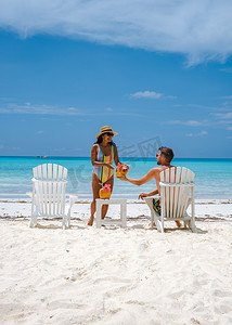 男女喝摄影照片_海滩上的男女情侣喝椰子饮料，普拉兰塞舌尔热带岛屿，海滩和棕榈树，安斯沃尔伯特塞舌尔海滩