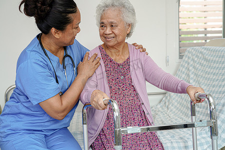 医生帮助亚洲老年妇女残疾患者在护理医院与助行器一起行走，医疗理念。