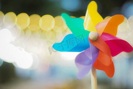 五颜六色的彩虹风车玩具与金色散景抽象有趣的背景。