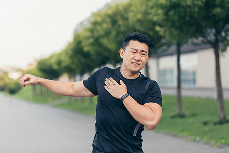 亚洲男运动员，在公园里揉肩痛，手臂肌肉酸痛
