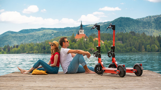 年轻夫妇在假期探索绿色国家斯洛文尼亚时，使用电动滑板车作为现代生态交通工具。