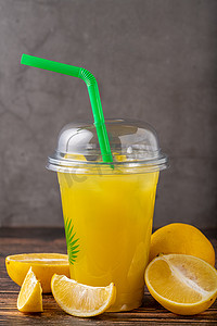 外卖玻璃杯中的柠檬水，旁边是木桌上的切柠檬