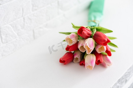 粉色婚礼背景设计摄影照片_白色背景中用纸包着不同颜色花朵的春郁金香花束