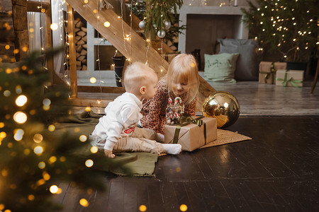 友谊装饰摄影照片_弟弟和妹妹在圣诞节前夕在为新年假期装饰的漂亮房子里玩耍。