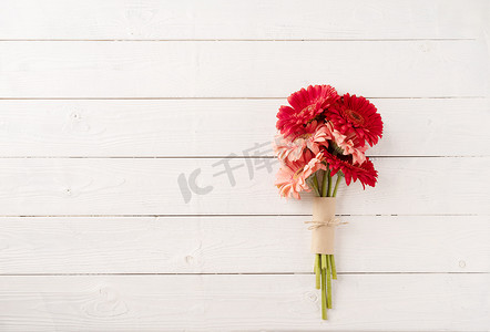 在白色木桌上的红色大丁草雏菊花