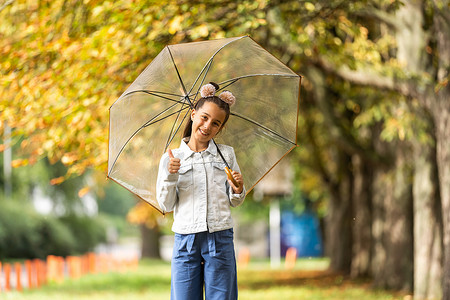 秋季公园雨中带伞行走的小孩
