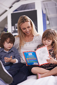 母亲读书摄影照片_一个一起读书的家庭……一位母亲和她的孩子在家读书。