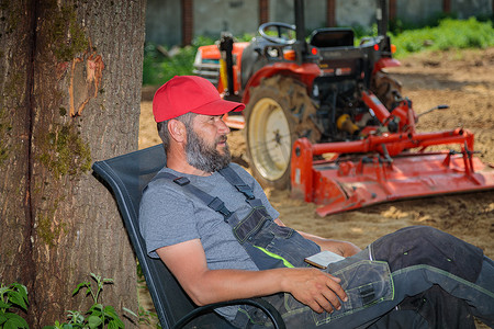 拖拉机司机犁地后在树荫下休息。