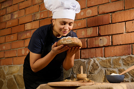 西班牙裔女面包师在阿里萨纳尔家庭面包店嗅着传统自制新鲜烘焙全麦面包的面包