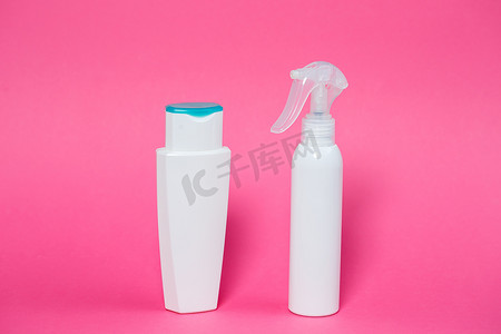 两个白色瓶子，里面有洗发水、身体凝胶、粉红色背景的皮肤喷雾