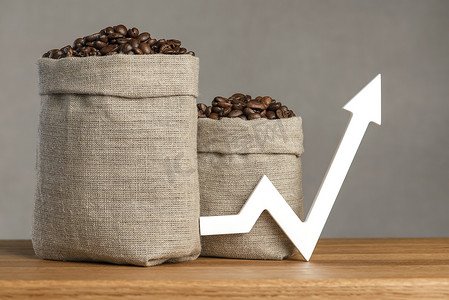 生长的咖啡豆摄影照片_一袋咖啡豆和一个向上的图表箭头。