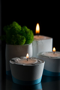 台中摄影照片_白色和蓝色混凝土烛台中的蜡烛和苔藓