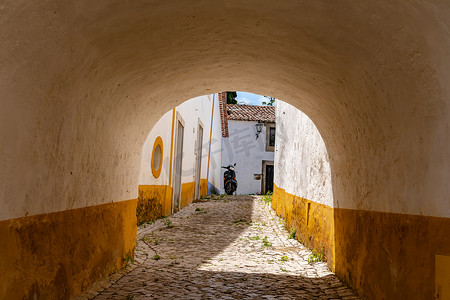 葡萄牙奥比都斯城堡，一条狭窄的小巷通过城墙上的通道通向更多的房屋